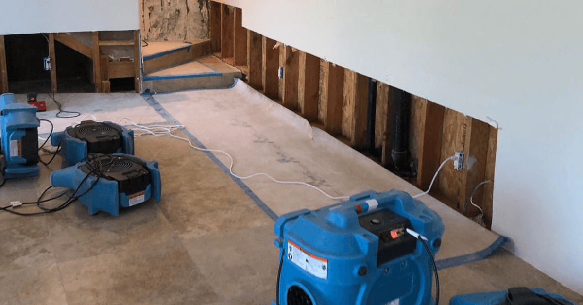 Structural drying equipment including air movers and dehumidifiers drying water damaged walls and floors inside residential home
